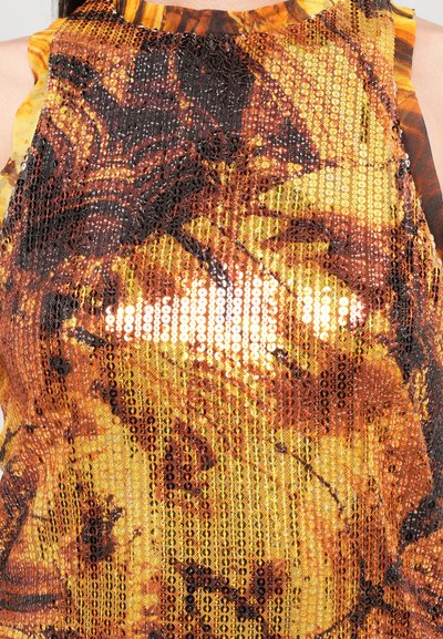 Sequin top with a vibrant orange and yellow pattern. Textured surface with shiny sequins and ruffled neckline detailing.