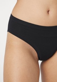 Fekete pamut bikini bugyi sima derékkal, zökkenőmentes kialakítással és minimalista varrási részletekkel a kényelem és a diszkrét viselet érdekében.