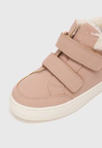 Adidași sintetici roz cu două benzi velcro, căptușeală din blană moale și o talpă din cauciuc alb texturat, oferind un design contemporan.