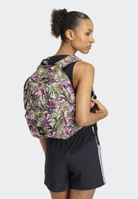 Zaino con motivo floreale in tonalità rosa e verde, spallacci imbottiti e esterno resistente. Presenta un design vivace con fiori e uccelli.