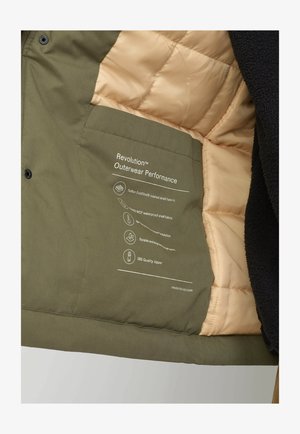 Groene buitenjas met een interieur van beige gewatteerde voering, voorzien van een etiket met informatie over de materialen en prestatiegegevens. Gestructureerde stof.