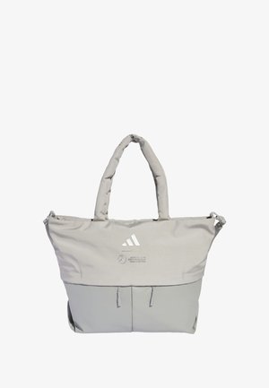 Šedá taška z látky s dvoma pevným rukoväťami. Má svetlejšiu sivú spodnú polovicu, zips na vrchu a potlačené logo na prednej strane.