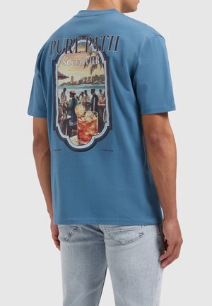 Blauwe katoenen t-shirt met een grote afbeelding op de achterkant van een cocktailscene en de tekst "PURE PATH SOCIAL CLUB" boven het ontwerp.