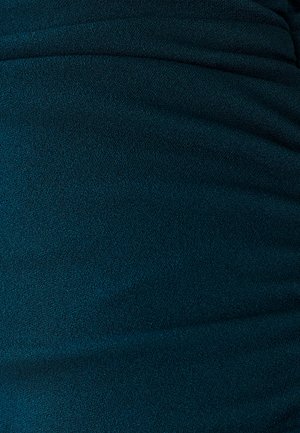Tissu stretch teal avec une texture lisse, présentant des détails pliés et un subtil éclat, adapté aux vêtements ajustés.