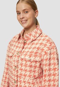 Rood en crèmekleurig houndstooth jack van textiel met structuur, voorzien van een hoge kraag, knoopsluiting en twee voorzakken met ronde knopen.