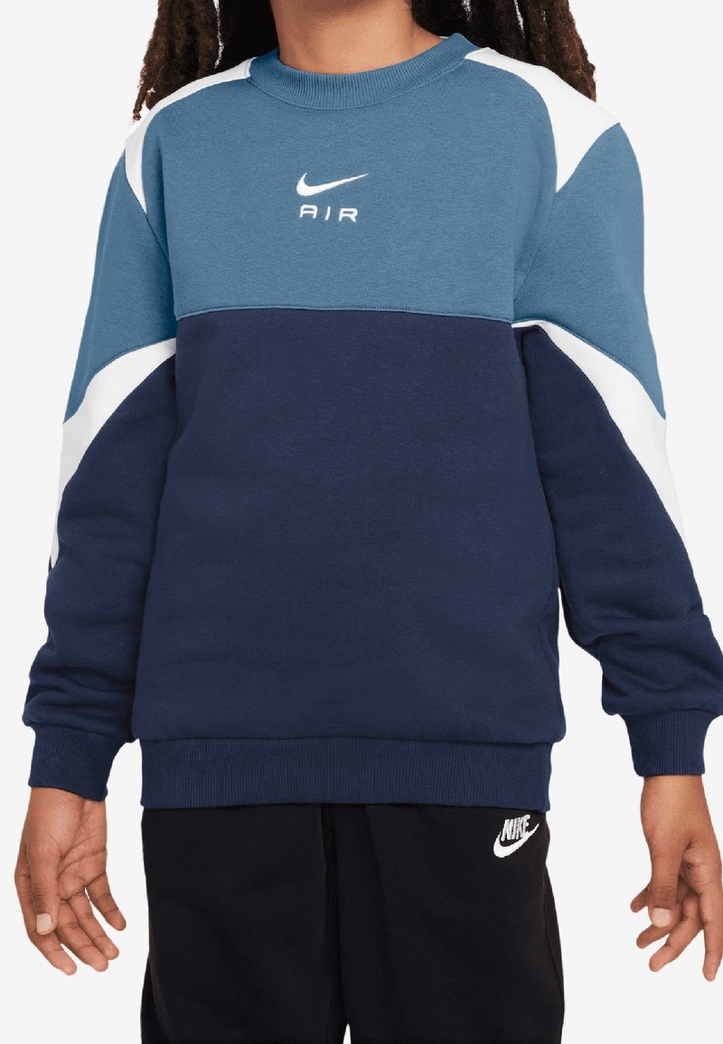 Bluza Nike w kolorze niebieskim i granatowym, z białymi akcentami, okrągłym dekoltem, ściągaczami na rękawach oraz logo nadrukowanym na piersi. Miękka, teksturowana tkanina.