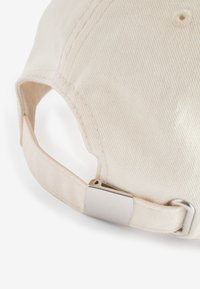 Crème-kleurige katoenen pet met een gestructureerd oppervlak, uitgerust met een metalen verstelbare sluiting op de band voor een veilige pasvorm.