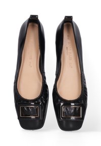 Zwarte gepatineerde leren ballerina's hebben een ronde neus en een grote vierkante gespaccent op de wreef. De binnenkant is beige met subtiele stiksels.