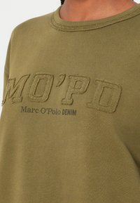 Felpa verde oliva realizzata in tessuto morbido, con lettere ricamate "MO’PD" e "Marc O'Polo DENIM" in cuciture a contrasto.