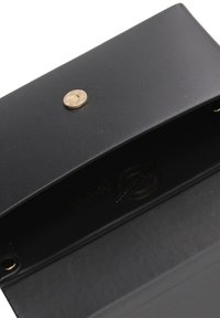 Porte-monnaie en cuir noir en forme d'enveloppe avec un fermoir à pression doré. L'intérieur présente un détail en logo embossé et une texture lisse.