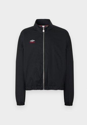 Fekete cipzáras kabát elasztikus mandzsettákkal és szegéllyel, álló gallérral és a bal mellkason fehér és piros Umbro logóval.