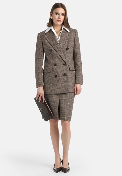Brown plaid double-breasted blazer with large buttons, paired with a matching knee-length skirt, and black patent leather heels.