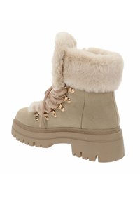 Botín de ante beige hasta el tobillo con puño de piel sintética, ojales dorados y suela de goma gruesa con un patrón de relieve. Cordones con un diseño trenzado.