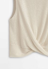 Beige ilmanhihaista toppia, joka on valmistettu teksturoidusta kankaasta ja jossa on kierretty etuosa ja sivutasku. Suora pinta ja rento malli.