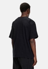 Sort bomulds T-shirt med en afslappet pasform, korte ærmer og rund hals. Har en glat tekstur og et rent, enkelt design.