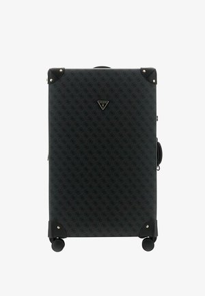 Grande valise rigide noire avec surface à motifs, protections d'angle noires, quatre roues et plaque centrale avec le logo Guess USA.