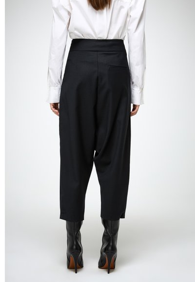 Zwarte high-waisted broeken met een relaxte pasvorm, voorzien van zijzakken en een gladde textuur, gecombineerd met kniehoge zwarte leren laarzen.