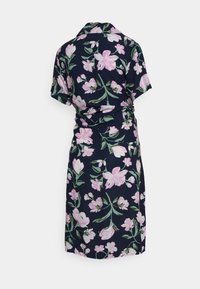 Vestido envelopado floral com fundo azul-marinho, apresentando grandes flores rosas e brancas. Mangas curtas, gola e detalhe de cintura atada.