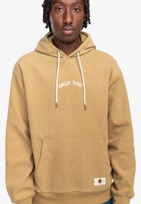 Beige corduroy hoodie with front pocket, white drawstrings, and "ONLY YOU" embroidered in a semi-arch. Textured and slightly oversized fit.