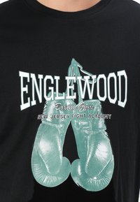 Black shirt with teal boxing gloves graphic and white text reading "Englewood Boxing Gym New Jersey Fight Academy" on front.