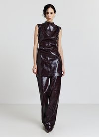 Weinrotes, glänzendes ärmelloses Top aus Vinyl mit hohem Kragen, kombiniert mit weit geschnittenen Hosen, die eine glatte, glänzende Textur aufweisen.