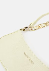 Yellow croc-embossed leather handbag with a smooth texture, featuring a gold chain strap and logo accents. Curved shape with a zipper closure.