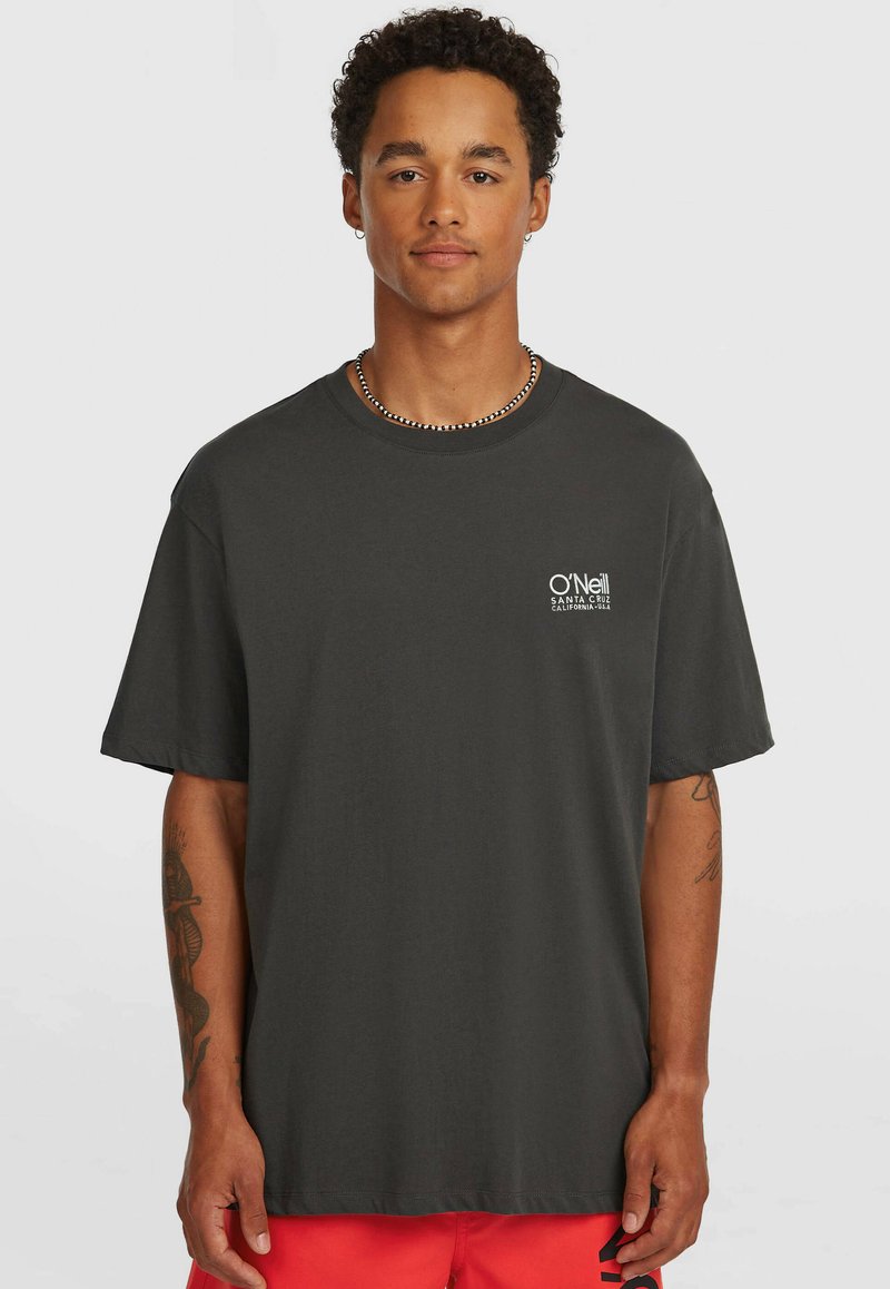 Σκούρο γκρι βαμβακερό T-shirt με άνετη εφαρμογή, που διαθέτει ένα μικρό λευκό λογότυπο στο αριστερό μέρος του στήθους. Κοντά μανίκια και στρογγυλή λαιμόκοψη.