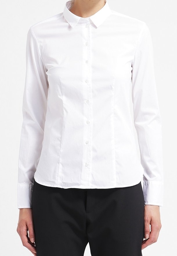 Camicia bianca con colletto a punta, maniche lunghe e vestibilità slim. Realizzata in tessuto liscio con una texture semplice.