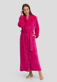 Bata de baño larga fucsia hecha de tejido de felpa, con cuello de chal, cierre de botones, cinturón ajustable y dos bolsillos laterales.
