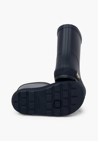 Bottes de pluie en caoutchouc noires avec une semelle texturée, une tige lisse et un motif en relief près du dessus ; présente un logo doré sur le côté.
