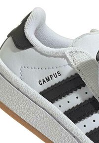 Weißer Sneaker mit schwarzen Lederakzenten und strukturiertem Gummisole. Verfügt über drei schwarze Streifen und das "CAMPUS"-Branding an der Seite.