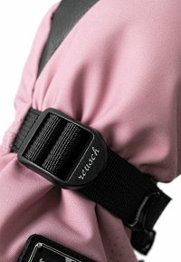 Rosa Stoffhandschuh mit einem schwarzen verstellbaren Riemen und Schnalle sowie "reusch"-Markierung. Die Textur ist glatt und hebt das weiche Material hervor.