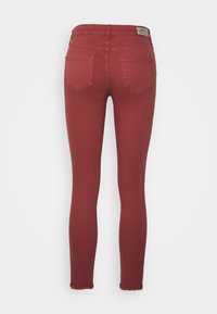 Jeans justos de cor bordô, feitos de denim. Apresentam uma cintura média, dois bolsos traseiros e uma bainha desfiada.