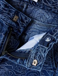 Denim tkanina s uzorkom ruža u tamnoplavoj boji. Ima srebrni patentni zatvarač i zakopčavanje na dugme. Unutrašnjost pokazuje bijelu podstavu.
