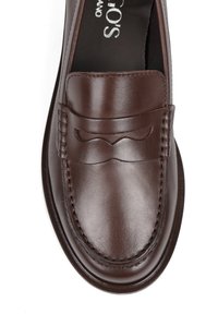 Brązowy skórzany mokasyn o gładkim wykończeniu, ozdobnym szwie i wypukłym wzorze falistym z przodu, z zaokrąglonym noskiem i wyściełaną wkładką.