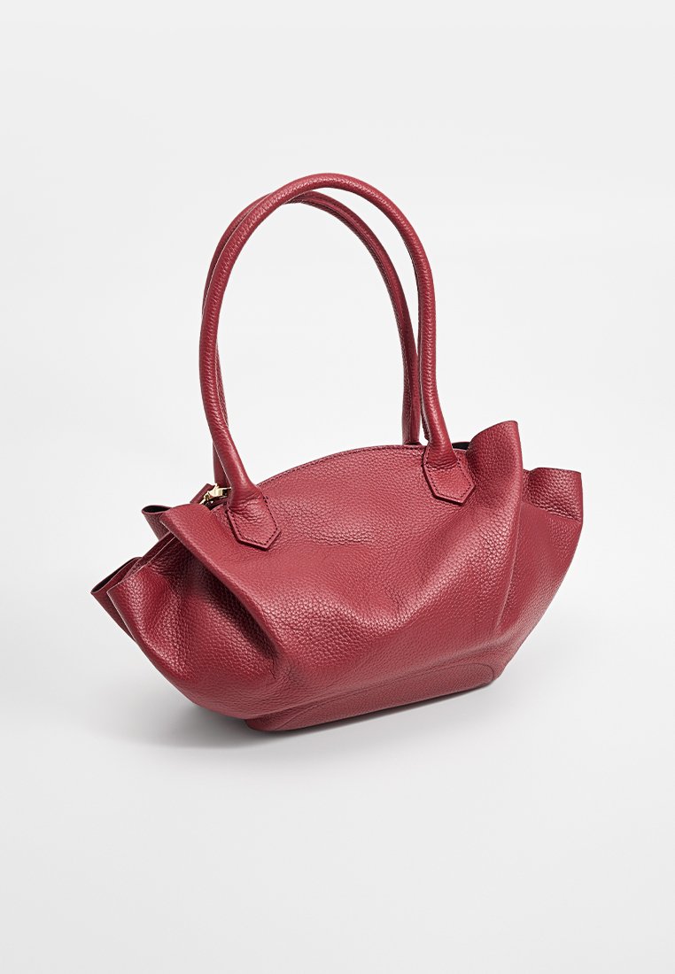 Borsa a mano rossa in pelle con superficie texturizzata, forma arrotondata, due manici e sottili pieghe nella parte superiore per un dettaglio di design unico.