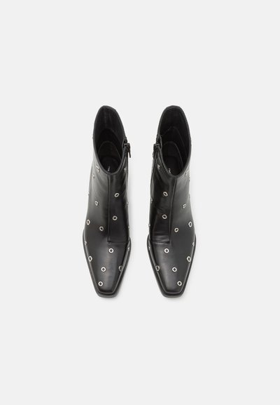 Botine negre din piele, cu vârful ascuțit, fermoar lateral și grommeturi metalice circulare pe laturi pentru un plus de detaliu.