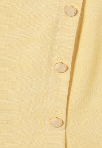 Tessuto giallo con superficie testurizzata, caratterizzato da quattro bottoni rotondi dorati lungo il lato e dettagli di cucitura bianca visibili.