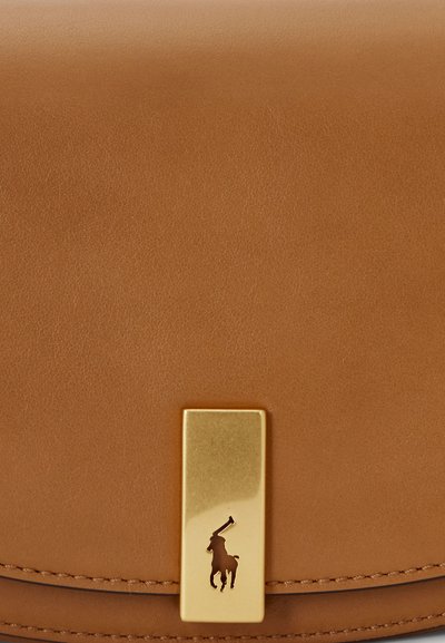 Karamelli nahast käekott, millel on sile tekstuur, ristkülikukujuline kuldne kinnisõlm ja embosed logo detail.