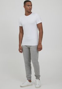 White short-sleeve t-shirt, gray joggers with a textured knit, and white sneakers. The outfit features a relaxed fit and neutral colors.