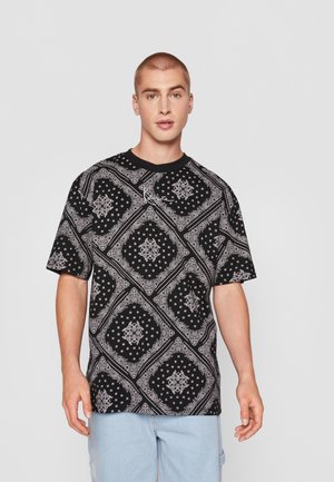 Schwarzes T-Shirt mit kurzen Ärmeln, das ein weißes Paisleymuster und geometrische Designs aufweist. Aus Baumwollmaterial mit Rundhalsausschnitt und lockerer Passform.