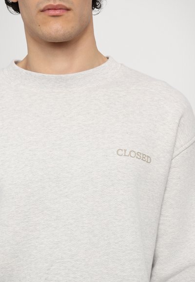 Light gray sweatshirt with a crew neck, featuring a ribbed collar and the word "CLOSED" embroidered in beige on the left chest area.