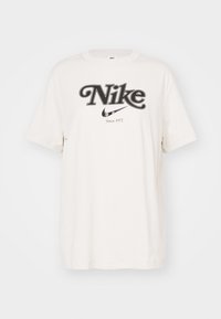 Krémové oversized bavlněné tričko s výrazným černým logem Nike a textem "Od roku 1972", s krátkými rukávy a kulatým výstřihem.