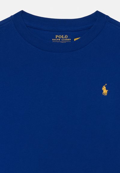 T-shirt en coton bleu avec un col rond et un petit logo de polo brodé jaune sur la poitrine. Texture du tissu lisse et uniforme.