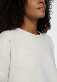 Helles graues Sweatshirt mit rundem Halsausschnitt und strukturiertem Stoff, auf dessen Vorderseite das Wort "HEUTE" dezent in Weiß gestickt ist.