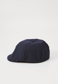 Navy blue cap made of textured fabric, featuring a button on top and a subtle logo on the side. Structured shape with curved brim.