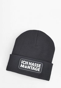 Dark gray ribbed beanie with a fold-over design, featuring a white rectangular patch that reads "ICH HASSE MONTAGE" with a cartoon graphic.