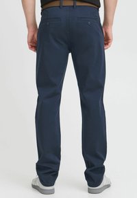 Chinos azul marino de algodón, con un corte recto, dos bolsillos traseros con botones y una textura suave. Calzado casual mostrado.