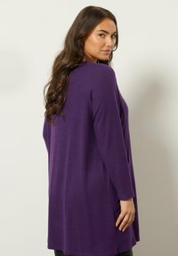 Cardigan viola a maniche lunghe realizzato in tessuto morbido, con una vestibilità comoda, aperture laterali e orlo arrotondato, ideale per il layering.