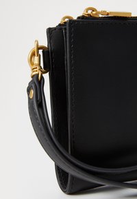 Black leather handbag with a smooth texture, featuring gold hardware accents and a detachable strap. Compact design with a zip closure.